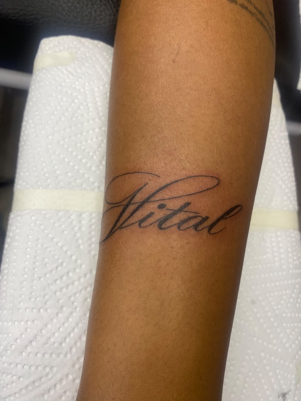 Flowing Vital script tattoo on a forearm