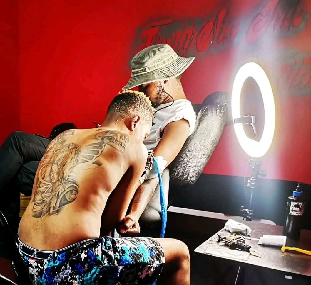 A tattoo session inside Ink Slave's red-walled studio